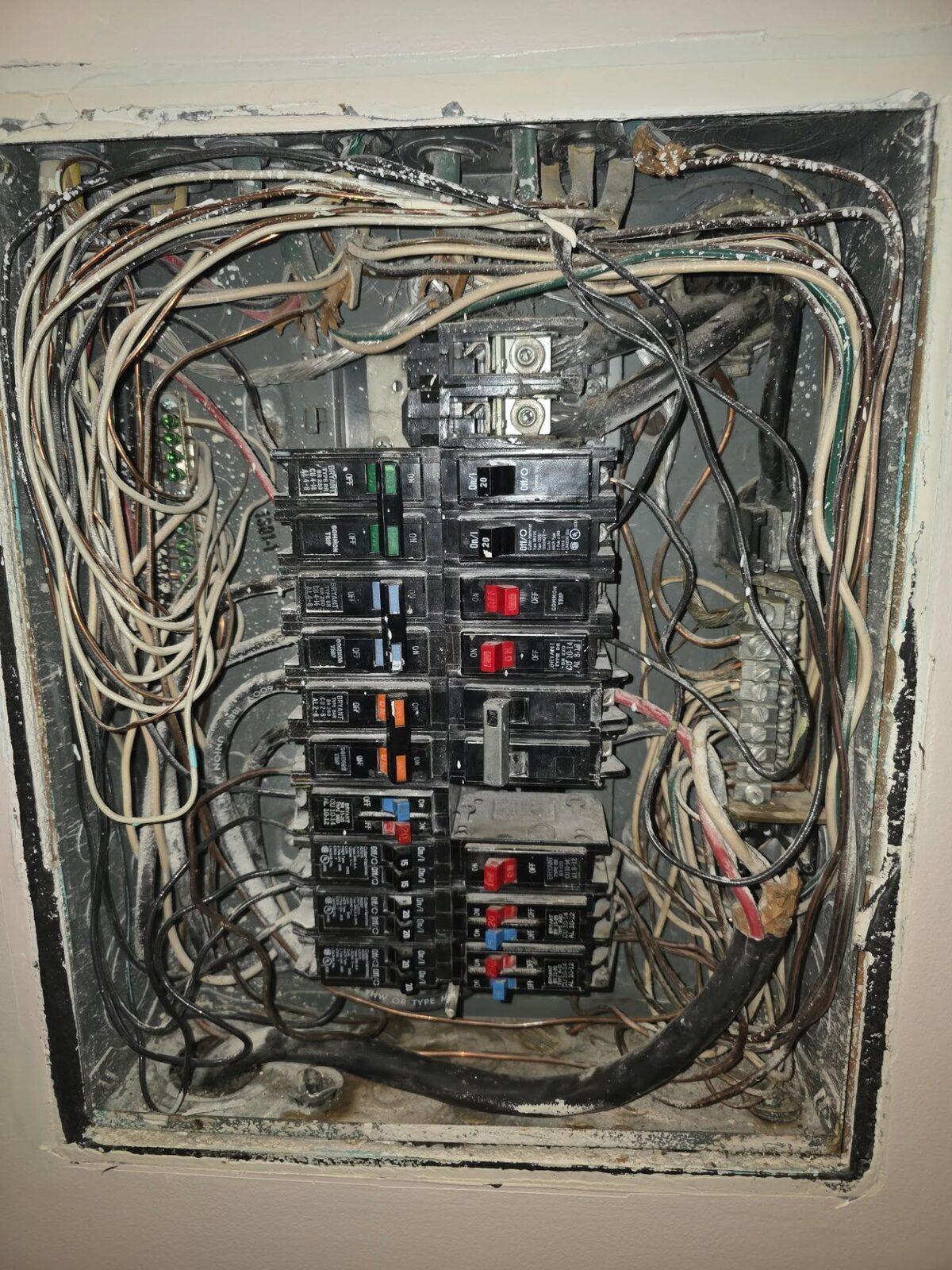 An old, overcrowded panel with tangled aluminum branch wiring and worn breakers before replacement